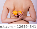 Naked woman back with an orange fruit the isolated image 126594341