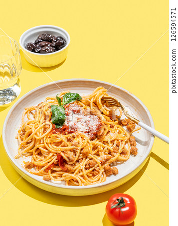 Spaghetti bolognese with tomato sauce, basil and parmesan cheese on yellow background 126594571