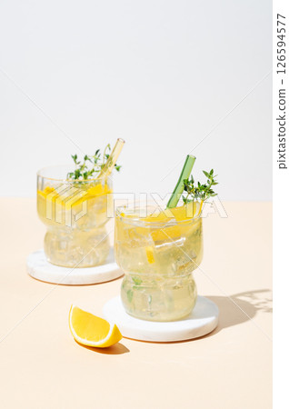 Two glasses of fresh drink lemonade with lemon, thyme and ice on a light background with shadows. 126594577