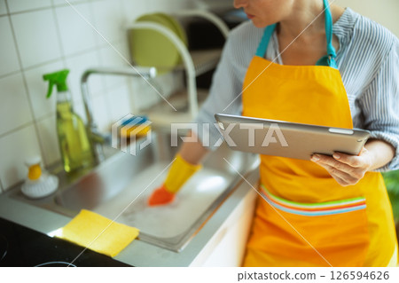 Woman Cleaning Sink with Tablet Guide Woman Cleaning Sink with Tablet Guide 126594626