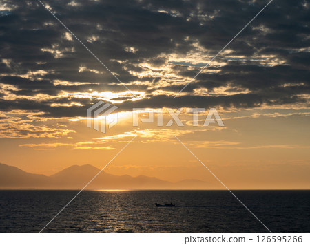 The sea at dusk and a fishing boat in the distance 126595266