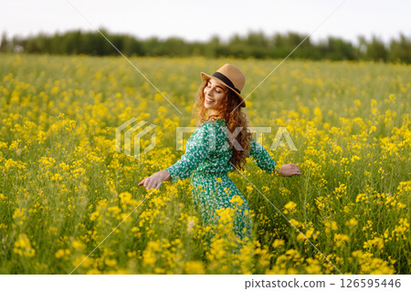 Young woman walking flowering field gently touch yellow flowers. Summer landscape. 126595446