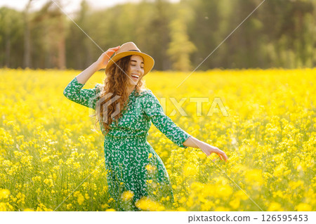 Beautiful woman in bright dress and elegant hat walks and has fun in rapeseed field. Nature, rest. Beautiful woman in bright dress and elegant hat walks and has fun in rapeseed field. Nature, rest. 126595453