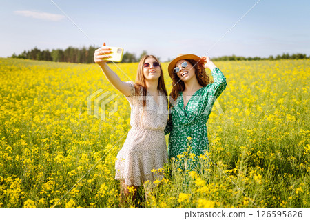 Selfie time.Two Young woman takes selfie while walking flowering field. Nature, relax and lifestyle. Selfie time.Two Young woman takes selfie while walking flowering field. Nature, relax and lifestyle. 126595826