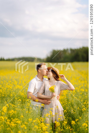 Young couple in love walks through a rapeseed field. The concept of love, test, relationship. Young couple in love walks through a rapeseed field. The concept of love, test, relationship. 126595890