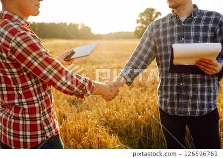 Handshake, joint work of farmers. Two farmers making agreement with handshake in wheat field. Handshake, joint work of farmers. Two farmers making agreement with handshake in wheat field. 126596761