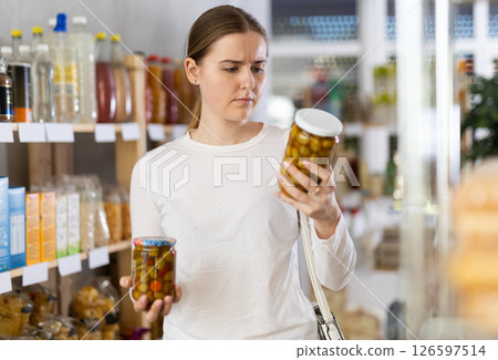 Young woman choosing olives at a display case Young woman choosing olives at a display case 126597514