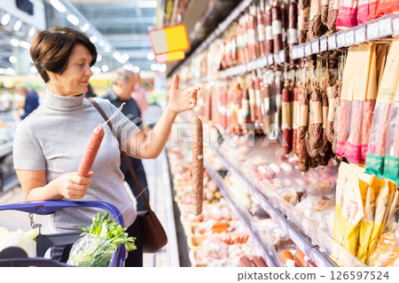 Elderly woman chooses sausage in supermarket Elderly woman chooses sausage in supermarket 126597524