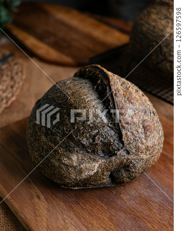 loaf of fresh baked black charcoal sourdough bread. Black ciabatta bread with activated carbon. loaf of fresh baked black charcoal sourdough bread. Black ciabatta bread with activated carbon. 126597598