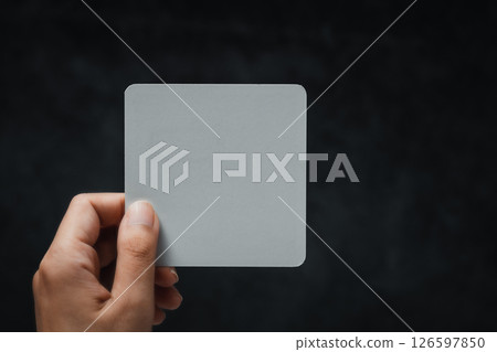 Woman's Hand Holding a White Note Against a Black Background Woman's Hand Holding a White Note Against a Black Background 126597850