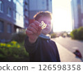 A child gives a flower in a green yard of a multi-story building 126598358