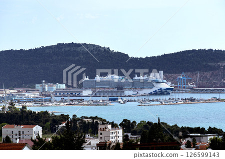 Cruise ship docked at port at dawn with marina and forested hills around Cruise ship docked at port at dawn with marina and forested hills around 126599143