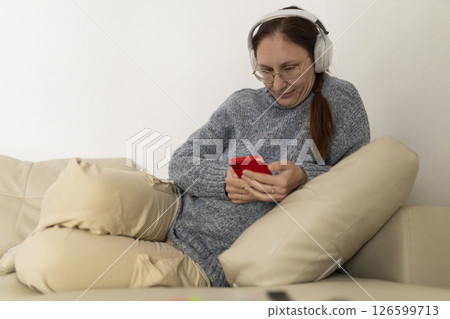 Woman relaxing on sofa using smartphone and wearing headphones 126599713