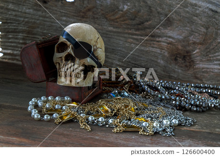 The pirate skull with treasure on wooden background. 126600400