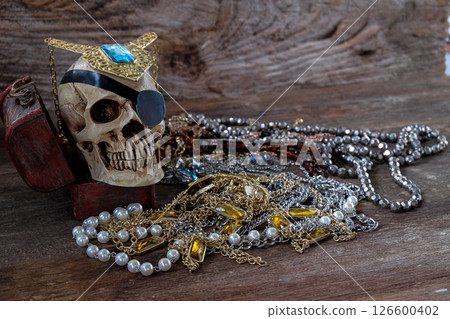The pirate skull with treasure on wooden background. 126600402