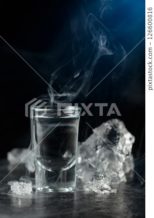 Crystal clear vodka or gin in a glass on a black stone table. 126600816