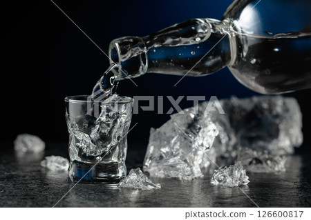 Crystal clear vodka or gin being poured into a glass. 126600817
