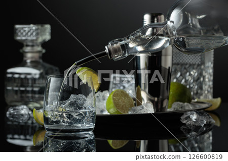 Vodka is poured into a glass with ice. Vodka is poured into a glass with ice. 126600819