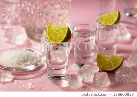 Tequila with lime, sea salt, and crushed ice on a pink background. Tequila with lime, sea salt, and crushed ice on a pink background. 126600830