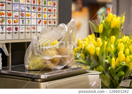 Retail customer weighing Pears in transparent plastic bag on digital scale in grocery store produce section illustrating shopping experience Retail customer weighing Pears in transparent plastic bag on digital scale in grocery store produce section illustrating shopping experience 126601262