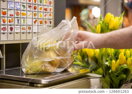 Retail customer weighing Pears in transparent plastic bag on digital scale in grocery store produce section illustrating shopping experience 126601263