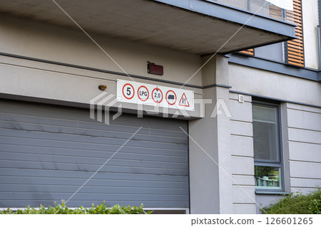 Regulatory signs above urban garage entrance display height width LPG and truck restrictions with warning informing drivers of access rules 126601265