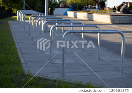 Row of simple metal bike racks on paved area in urban public space providing essential parking for bicycles Row of simple metal bike racks on paved area in urban public space providing essential parking for bicycles 126601275