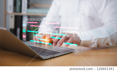 Businessman using project management software on a laptop to schedule tasks, update Gantt charts, and manage workflow, enhancing planning, productivity, and business progress. Businessman using project management software on a laptop to schedule tasks, update Gantt charts, and manage workflow, enhancing planning, productivity, and business progress. 126601341