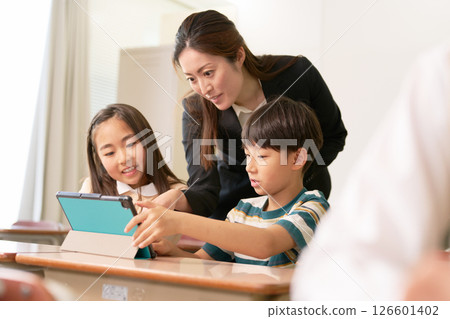 Elementary school students using tablets and teachers instructing them 126601402