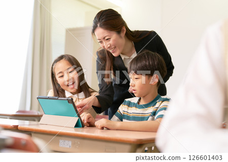 小學生使用平板電腦，老師指導他們 126601403