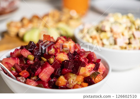 traditional vinaigrette salad with beets, potatoes, carrots, peas, and pickles in a white bowl, with olivier salad in the background on a festive table traditional vinaigrette salad with beets, potatoes, carrots, peas, and pickles in a white bowl, with olivier salad in the background on a festive table 126602510