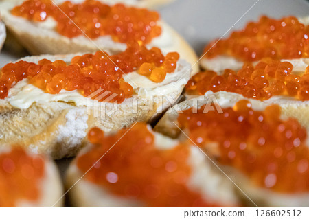 gourmet appetizer with fresh baguette slices, creamy butter, and glossy red caviar, served on a plate for an elegant and festive meal 126602512