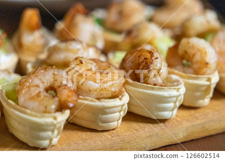 crispy tartlets filled with creamy cheese, fresh cucumber, and grilled shrimp, served on a wooden board as a gourmet appetizer crispy tartlets filled with creamy cheese, fresh cucumber, and grilled shrimp, served on a wooden board as a gourmet appetizer 126602514
