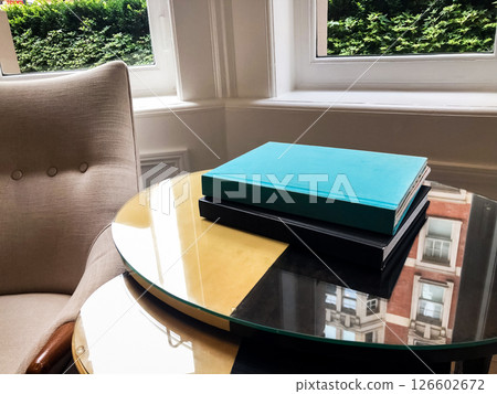 A book placed on a coffee table in the hotel lobby, creating a calm and inviting atmosphere. The soft light and elegant setting emphasize the peaceful and relaxed vibe of the space. A book placed on a coffee table in the hotel lobby, creating a calm and inviting atmosphere. The soft light and elegant setting emphasize the peaceful and relaxed vibe of the space. 126602672