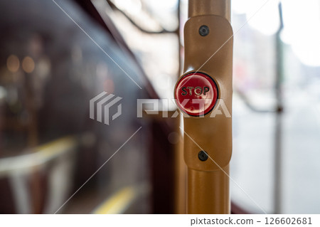 Close Up of the Red Stop Button on a London Bus with the City Street Visible Through the Window, Capturing the Everyday Commuter Experience. Close Up of the Red Stop Button on a London Bus with the City Street Visible Through the Window, Capturing the Everyday Commuter Experience. 126602681