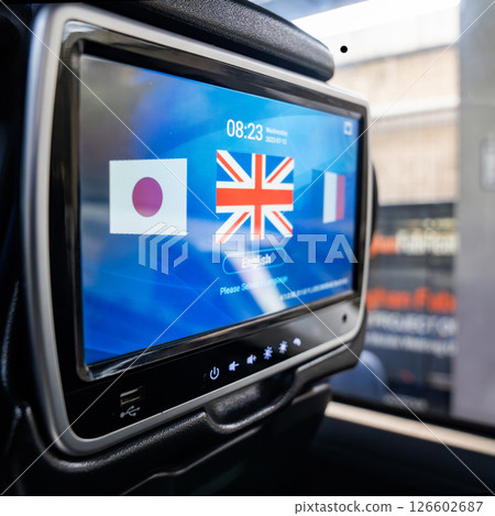 A language selection screen is displayed on a touch monitor mounted behind a bus seat. The interface shows flags and options for passengers to choose their preferred language while traveling. 126602687