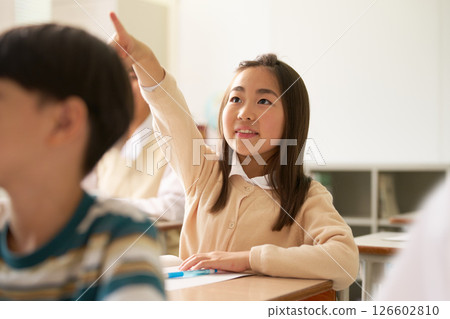 Female elementary school student raising her hand during class 126602810
