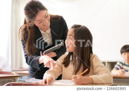 Elementary school students studying and a teacher with a smile Elementary school students studying and a teacher with a smile 126602995