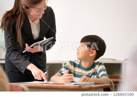 正在學習的小學生和微笑的老師 126603100