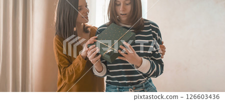 Two happy girls celebrate holiday, making nice gifts. 126603436