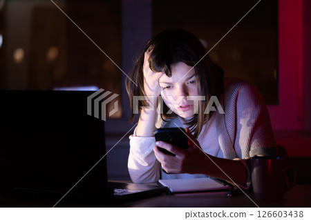 Girl works on a laptop at home at night. Girl works on a laptop at home at night. 126603438