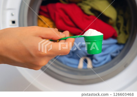 Female hand holds a cap with washing powder. Female hand holds a cap with washing powder. 126603468