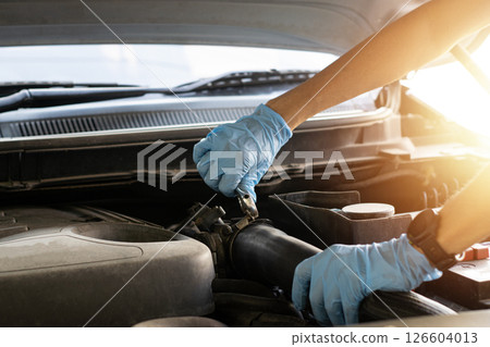 The mechanic is fixing the engine, using a wrench to tighten the nuts. 126604013