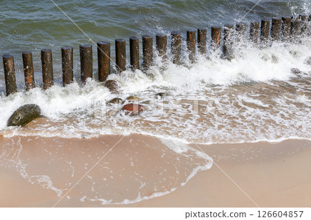 Wooden breakwater structures along a sandy beach with the ocean waves Wooden breakwater structures along a sandy beach with the ocean waves 126604857