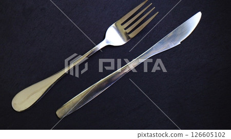 metal fork and knife on a black backgroun 126605102