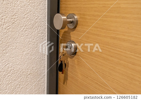 close-up of a modern wooden door with a key inserted into the lock, keychain hanging below 126605182