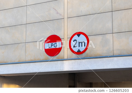LPG restriction and height limit traffic signs on a beige wall, indicating entry prohibition for LPG vehicles and a 2-meter clearance limit 126605203