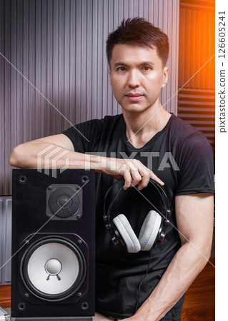 asian handsome male music producer posing with loudspeaker and headphone on audio diffuser background in studio 126605241
