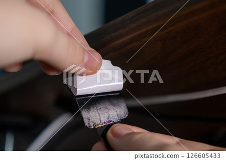 close-up of hand peeling adhesive backing from velcro strap for cable organization under wooden desk 126605433