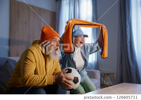 Excited elderly couple watching football match on tv 126605711